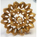 A textured yellow-metal brooch centred with a pearl in flower head design, the pin marked