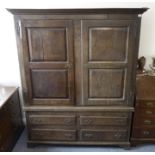 A large mid-18th century oak press cupboard; the outset cornice above two doors with fielded