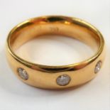 An 18-carat gold band ring set with three fine diamonds; ring size K (total weight 6.14g) (The