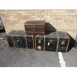 A pair of large wooden-bound travelling trunks together with one other slightly smaller metal-
