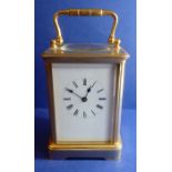 A gilt-metal and glass-sided carriage clock; white enamel dial with Roman numerals, the gilded