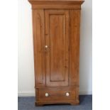 An early 20th century pine wardrobe of slim proportions; the outset cornice above a single