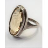 A silver ring centrally set with a hand-cut oval stone (possibly a citrine), boxed