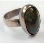 A silver ring centrally set with a polished cabochon hardstone of varying colours (boxed)