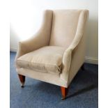A large and comfortable upholstered armchair on square tapering mahogany legs terminating in brass