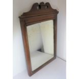 An early 20th century walnut-framed wall-hanging looking glass having broken swan-neck style