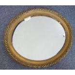 An early 20th century gilt-framed oval wall-hanging looking glass (frame size 75cm x 65cm) (the