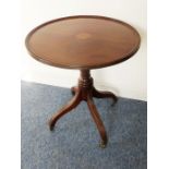 An antique circular-topped mahogany occasional table; turned stem and raised on four downswept