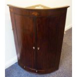 A large late 18th century bow-fronted mahogany and boxwood-strung wall-hanging corner cabinet; the