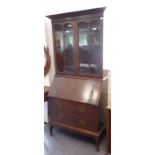 An early 20th century oak bureau-bookcase; the outset cornice above two glazed doors enclosing