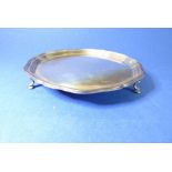 A small hallmarked silver salver with pie-crust edge and raised on three cast feet; Sheffield