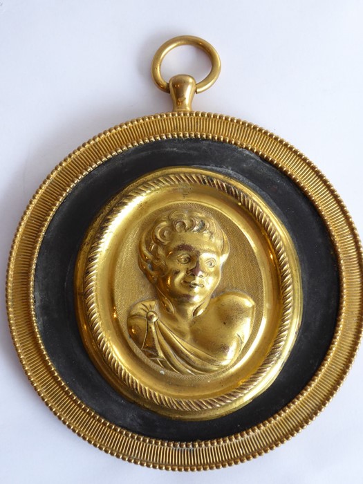 A 19th century circular gilt-metal wall-hanging relief study of a young male figure with curly