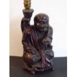 An early 20th century Chinese hardwood carving of a seated Lohan; in his left hand a long bead