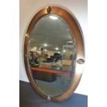 An early 20th century oval coppered framed wall-hanging looking glass