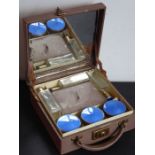 An early 20th century travelling vanity case; three glass bottles and three facet-cut jars with
