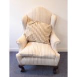 A Queen Anne style striped upholstered wingback armchair on large mahogany front legs; corner