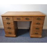 An early 20th century oak-topped pine pedestal desk, nine drawers and raised on plinth base (122cm