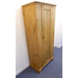An early 20th century stripped and waxed pine wardrobe of slim proportions; the panelled door