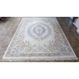 A very large Chinese woollen carpet; beige ground, the central blue ovals with swags and ribbons and