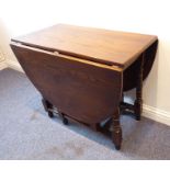 An oval drop-leaf oak occasional table