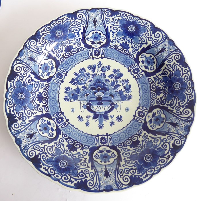 A large early 20th century Dutch Delft charger; the border decorated with flower heads and