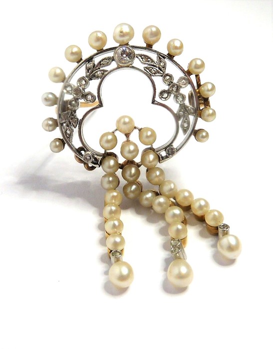 An Edwardian pearl and diamond-set brooch, of openwork design; the floral and foliate diamond-set