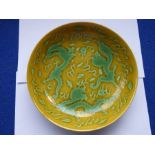 A Chinese porcelain scrafitto dish; three green dragons chasing pearls amongst clouds against an