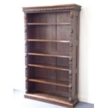 A late 19th century open oak bookcase; the cushion-shaped cornice carved with various style leaves