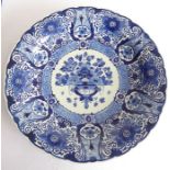 A large early 20th century Dutch Delft charger; the border decorated with flower heads and