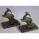 A pair of Art Deco period book ends modelled as naturalistic verdigris leaping gazelles, each on