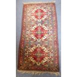 A hand-knotted Turkish rug; three large red and cream ground spreading lozenges within borders