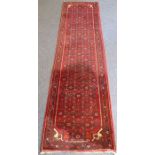 A long north-west Persia Hamadan runner with red ground (297cm x 84cm)