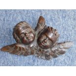 A small patinated carved wooden wall applique in 17th century-style depicting two cherubic-style