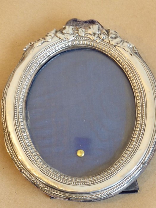 An easel-style silver photograph frame of oval section (damages) (18cm high)