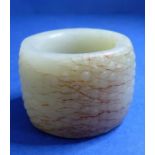 A celadon jade Manchu thumb ring carved with 'Rice Grain' pattern with 'Cow's Hair' markings in