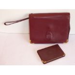 Cartier of Paris, a ladies burgundy-leather clutch bag, together with a Cartier calendar notebook,