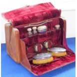 An early 20th brown-leather vanity case; two compartments, one compartment opening to reveal various