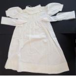 A circa 1950s baby's nightgown; ivory-coloured cotton, gathered front with sash ties, long sleeves
