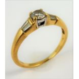 An 18-carat gold solitaire diamond ring set with baguette diamond shoulders; ring size M (total