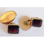 A pair of oval yellow-metal (one back marked) cufflinks, each mounted with an emerald-cut deep red