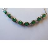 An emerald and diamond-set chain necklace; the front section set with eight oval-faceted claw-set