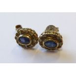 A pair of sapphire and diamond-set earrings each with oval-faceted collet-set sapphire within a