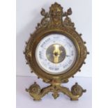 A 19th century gilt-metal aneroid desk barometer with easel-style stand; white dial below a stylised