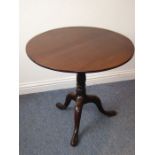 A George III period circular mahogany tilt-top occasional table; two piece top above turned stem and