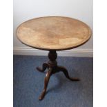 An early 19th century circular oak and dog-tooth banded tilt-top occasional table; turned stem