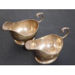 A pair of Georgian-style hallmarked silver sauce boats, each with leaf-capped scrolling handle and