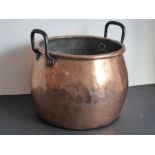 A large 19th century cauldron-shaped copper cooking pot of ovoid form and with two cast-iron handles