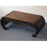 A late 19th/early 20th century Chinese hardwood low table; the fielded panelled top rebating into