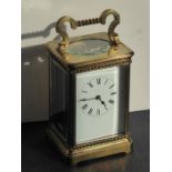 An early 20th century brass carriage clock timepiece; the swing handle above an enamel dial with