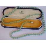 A 1930s Art Deco-period string of graduated green glass jade-coloured beads; the clasp mounted